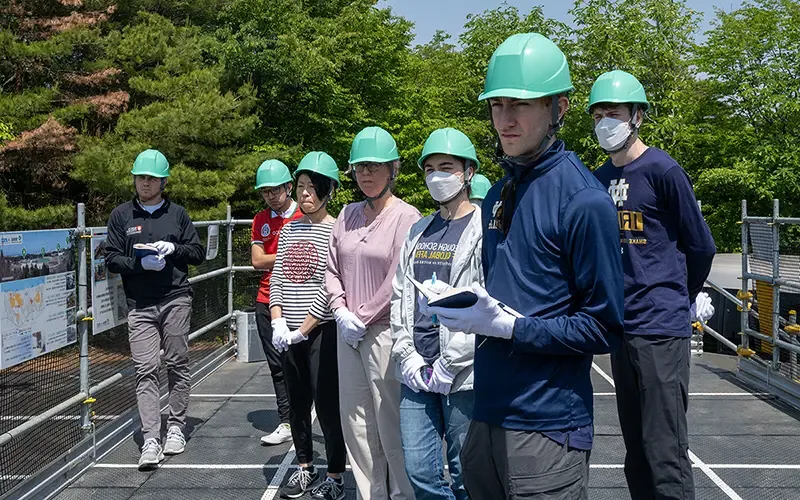 While wearing hardhats, the Notre Dame team listens as a TEPCO representative explains the layout of the nuclear plant and the events that led to the meltdown.
